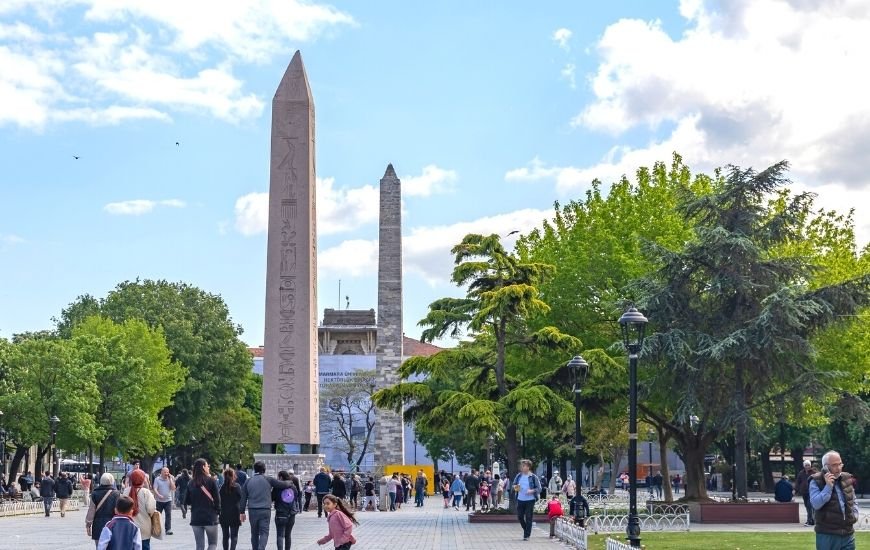 Turistas recorriendo el Hipódromo de Constantinopla en el centro histórico de Estambul, rodeados de monumentos históricos.