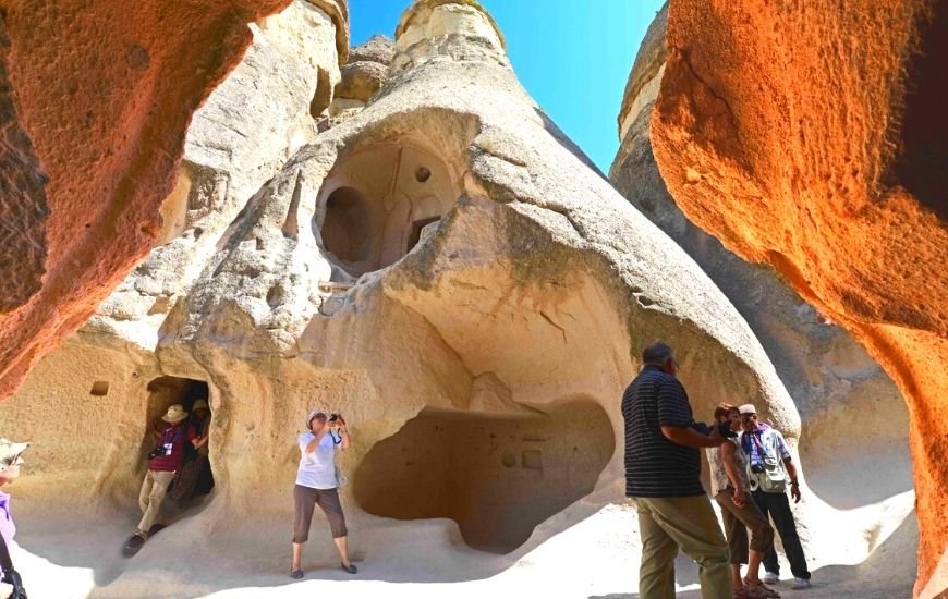 Visitantes explorando las antiguas viviendas excavadas en las formaciones rocosas de Capadocia