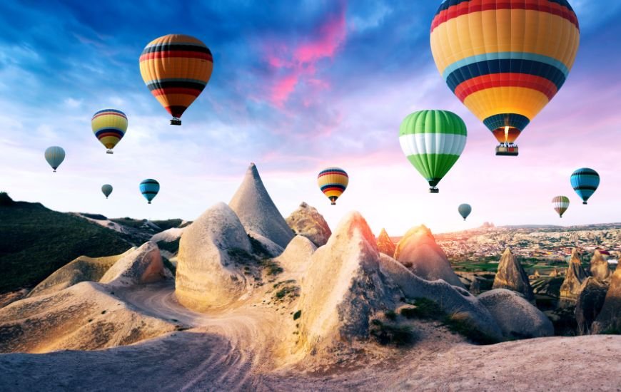 Globos aerostáticos sobrevolando las características chimeneas de hadas en Capadocia al amanecer.