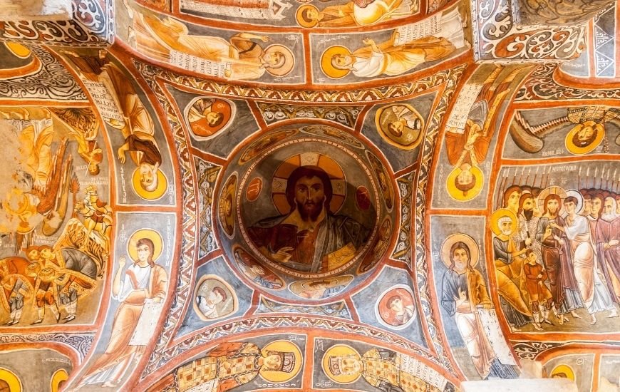 Frescos antiguos con figuras religiosas en la cúpula y paredes de una iglesia rupestre de Capadocia