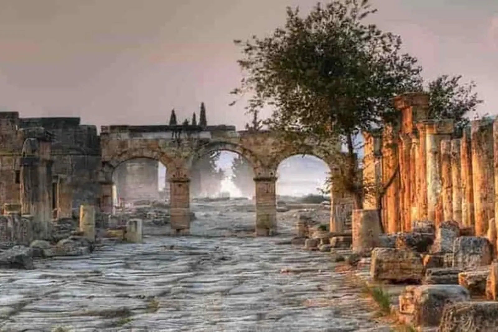 Ruinas de la antigua ciudad con arcos de piedra y columnas al atardecer