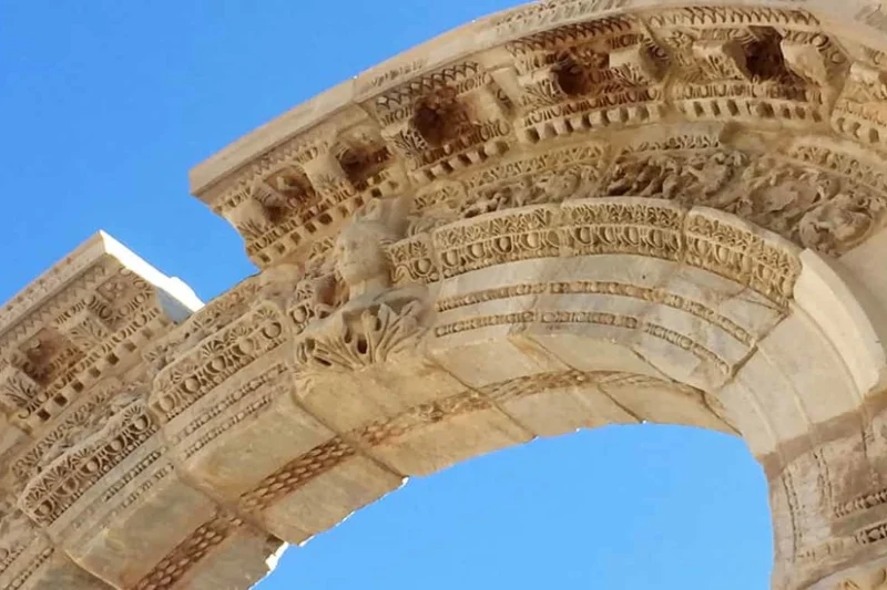 Detalle escultórico en un arco romano antiguo bajo un cielo claro puro