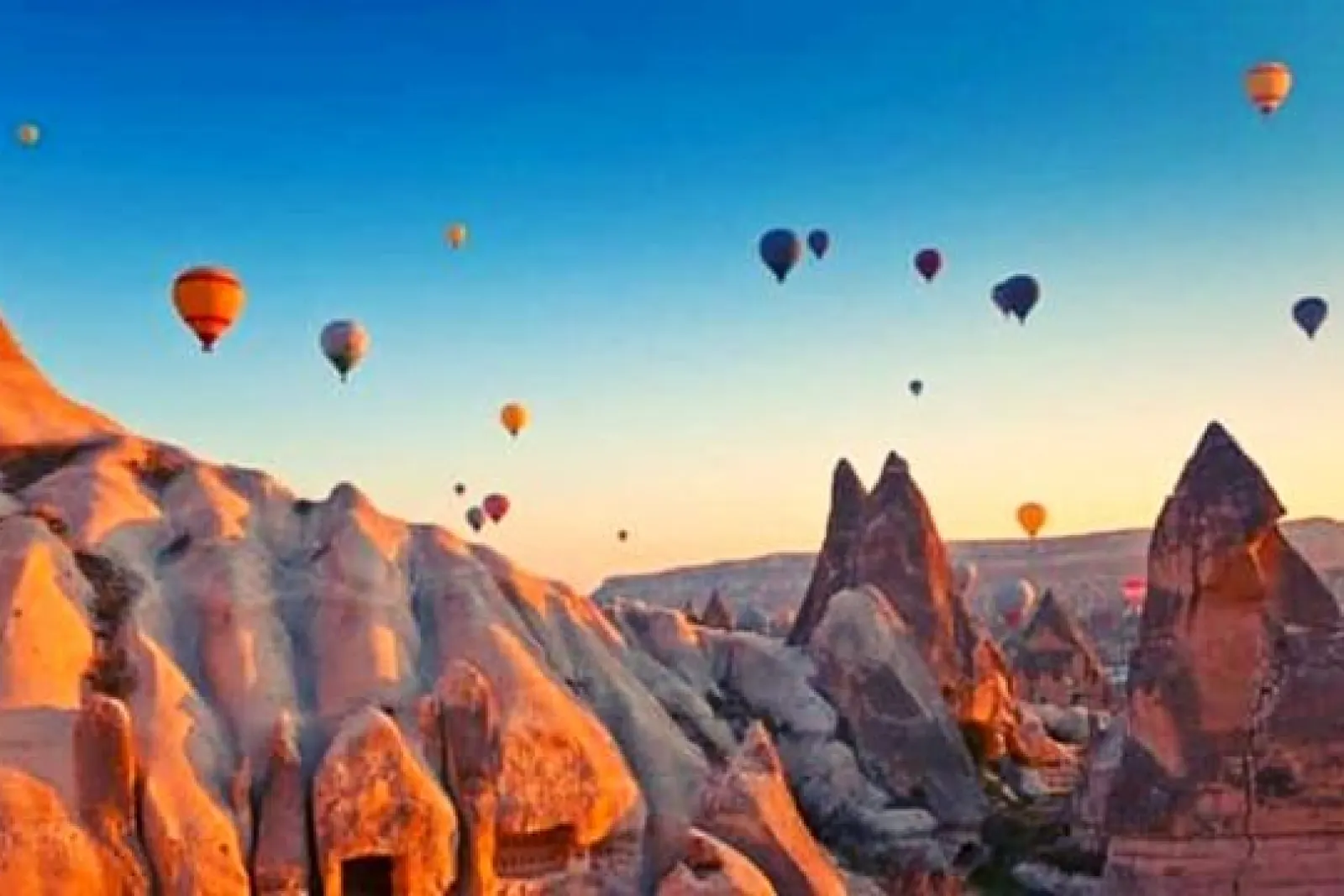 Globos aerostáticos volando sobre las chimeneas de hadas al amanecer en Capadocia