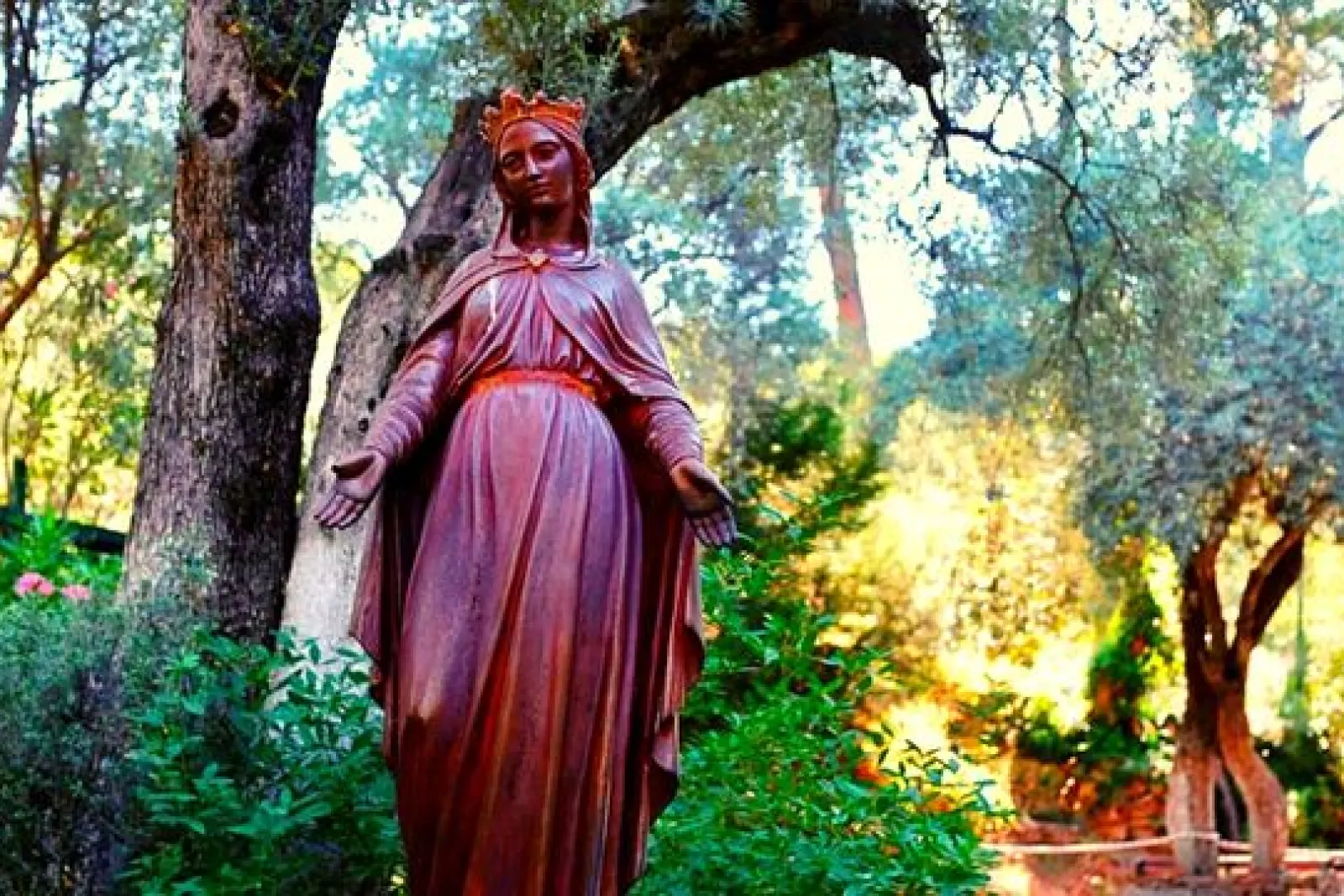 Estatua de la Virgen María en el recinto de la Casa de la Virgen María, cerca de Éfeso, rodeada de árboles y vegetación.