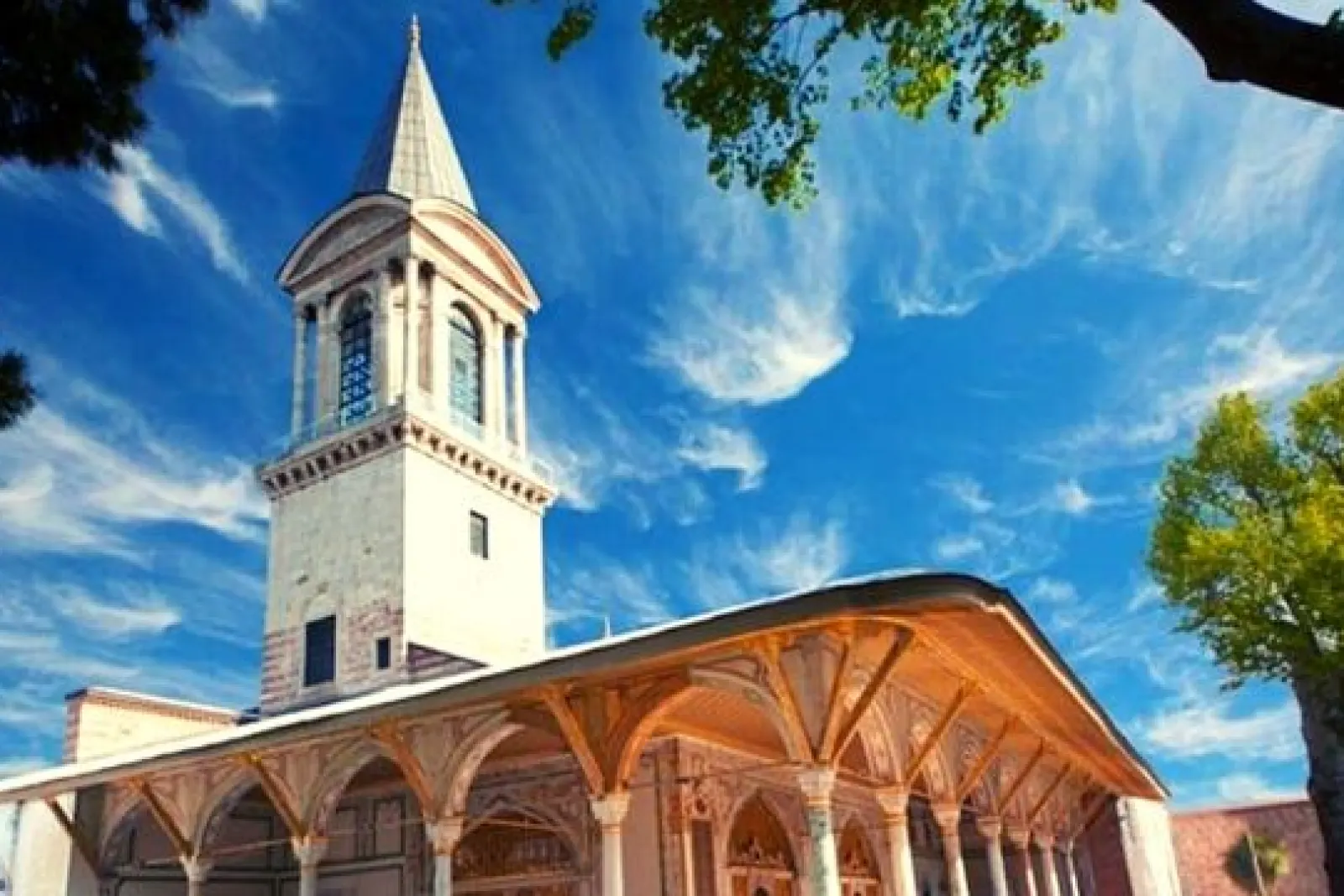 Torre y galería porticada del Palacio de Topkapi en Estambul bajo un cielo azul brillante.